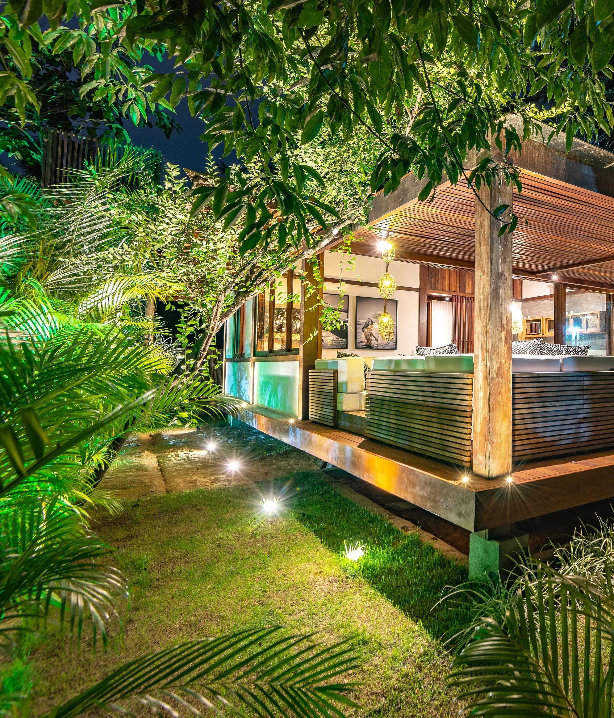 Fachada iluminada da Residência 4 entre o gramado e o jardim tropical