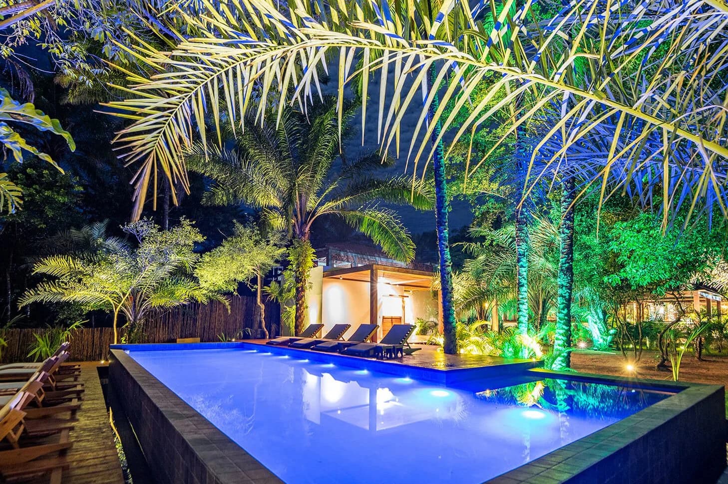 Piscina de borda infinita iluminada à noite no Colibri Beach Villas